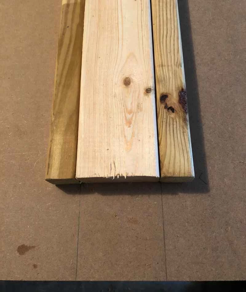 一塊中密度纖維板上，有一根2x4的木條，兩側各有一根1x1的木條。