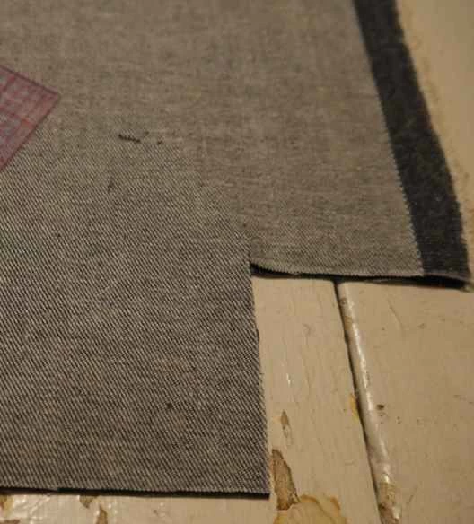 牛仔布布料，剪開一個角，形成一個側邊，用來製作一個用回收布料製成的DIY拉鍊手提袋。