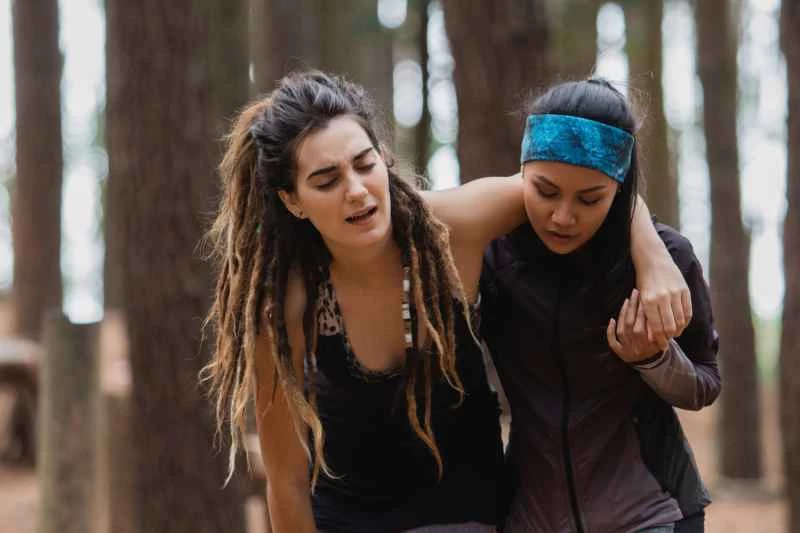 一位女士攙扶著在運動中腿部受傷的朋友行走