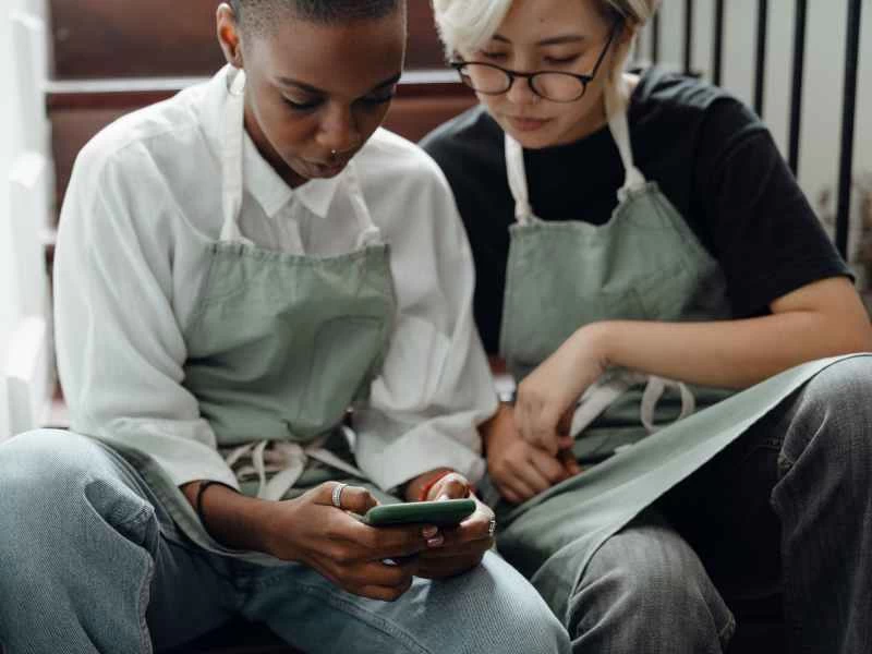 兩個人坐在樓梯上，用手機看影片。