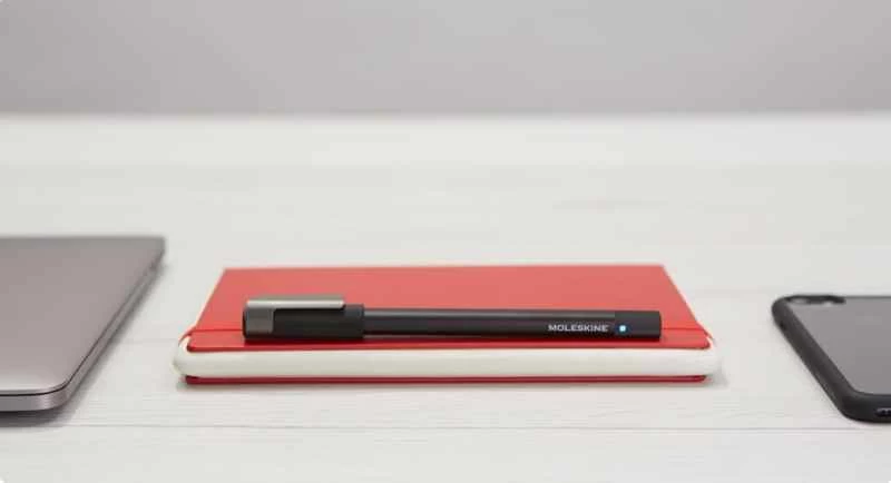 一支黑色 Moleskine 鋼筆和一本紅色平板電腦筆記本，可以用來將手寫筆記數位化。