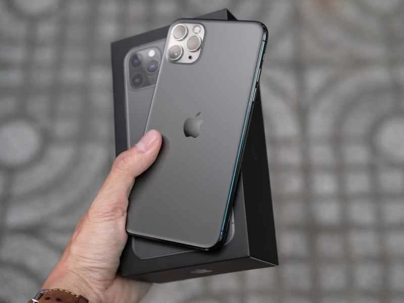 一手拿著一部 iPhone 11 和它的包裝盒