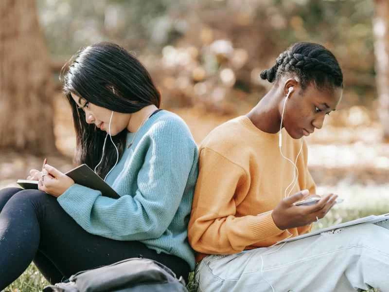 一群年輕人背對背坐在公園裡，用手機學習。