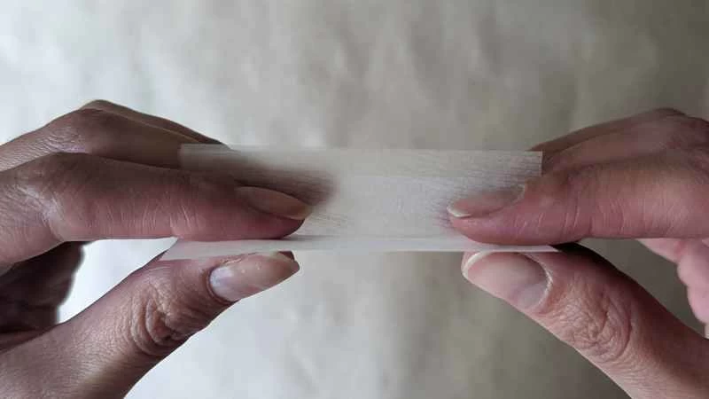 雙手拿著捲菸紙，準備捲菸。