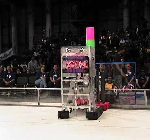 在 2009 年紐約舉行的 FIRST 機器人競賽中，一個高大的矩形機器人站在競技場內，台下觀眾眾多。