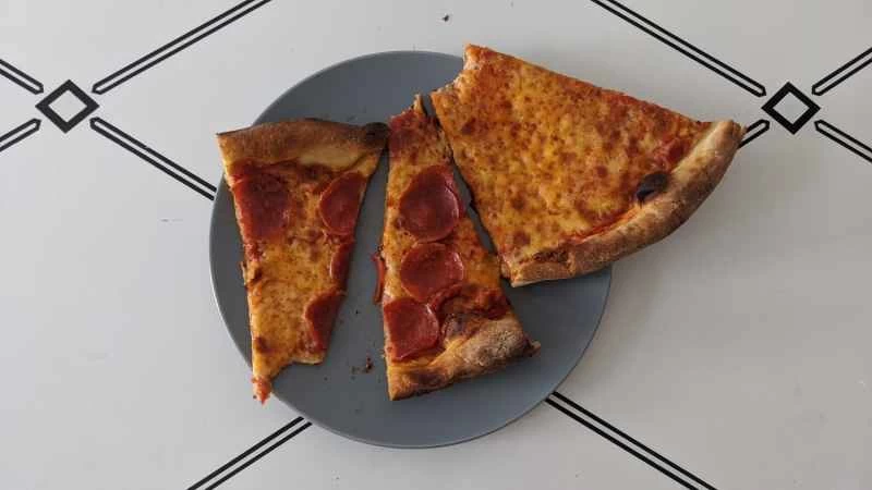 在關於如何重新加熱披薩的實驗中，三片披薩被微波爐加熱後放在藍色盤子上。