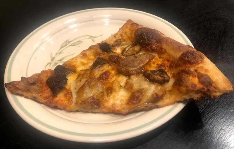 一塊香腸、蘑菇和洋蔥披薩，有人選擇用氣炸鍋加熱。