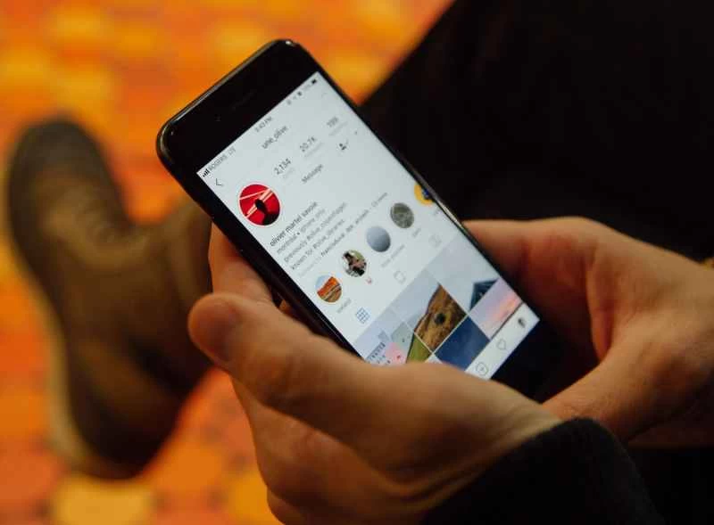 一手拿著手機，螢幕上顯示Instagram