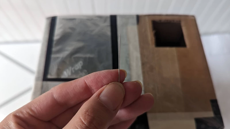 手指握著一根針，對著針孔相機。