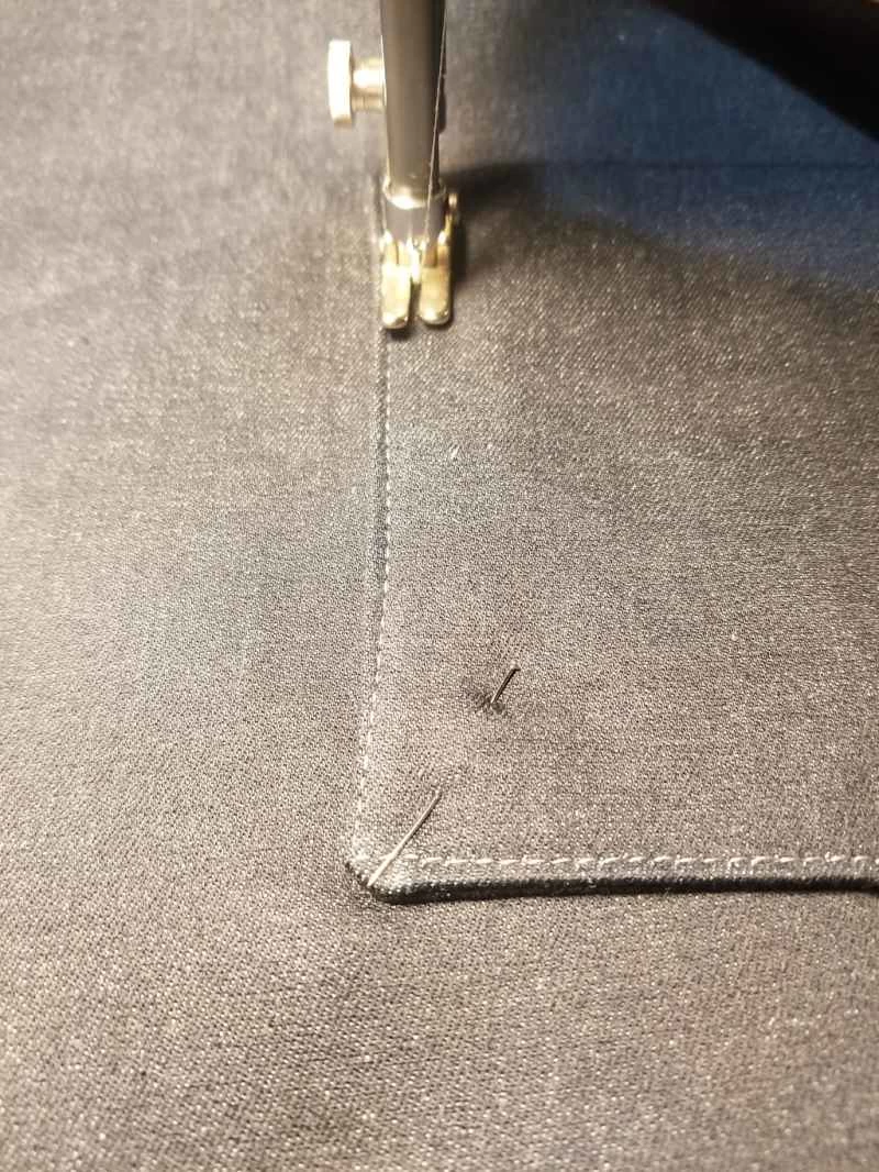 一台縫紉機正在用剩餘布料縫製一個自製拉鍊手提袋，袋子上正在縫製一個口袋。