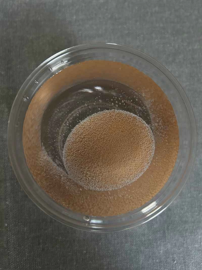 在一杯醋中，一顆棕色雞蛋周圍環繞著細小的氣泡。