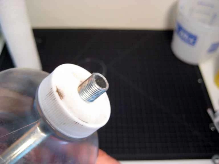 一個塑膠瓶蓋，裡面伸出一根螺紋的金屬桿。