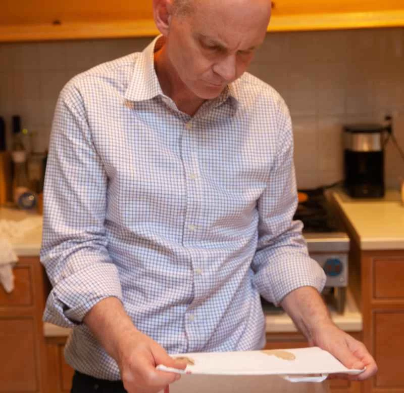 一名男子正在檢查一塊沾滿污漬的廚房抹布，克里斯伊萊